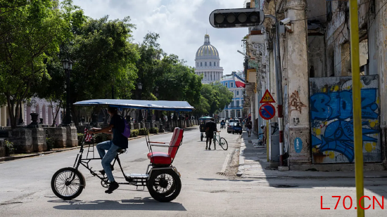 2026 年 3 月 4 日，哈瓦那，一辆三轮车驶过因停电而失灵的交通信号灯。